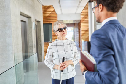 senior woman with cane in office building talking to a man